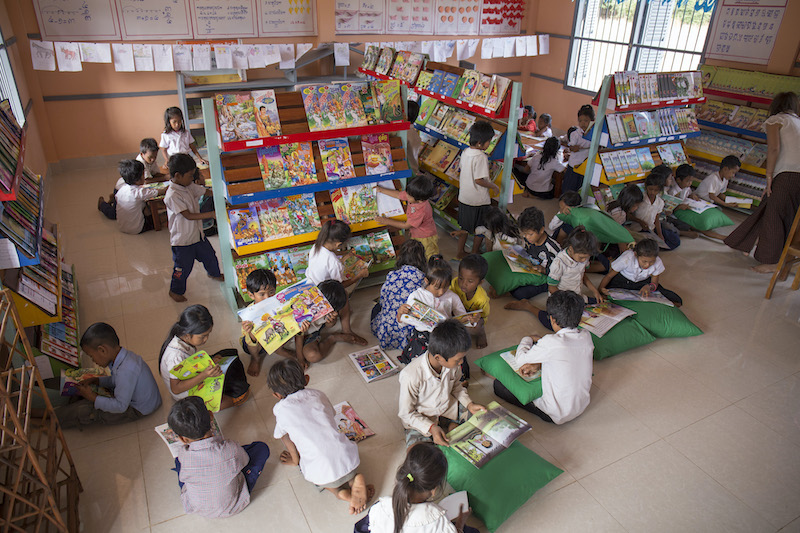 Kinder in einer Schulbibliothek mit Kissen und Büchern