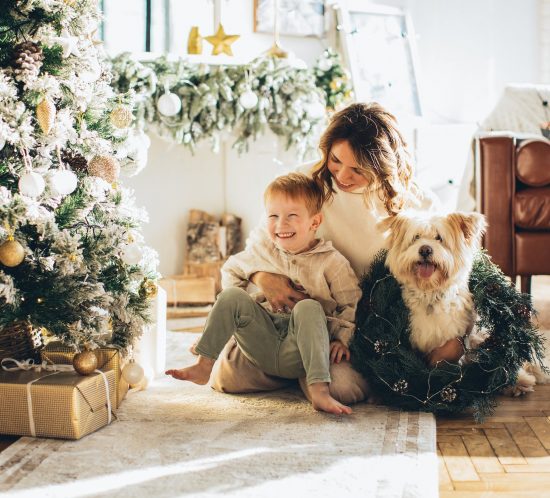 Niño sentado con su madre y su perro alrededor del árbol de Navidad