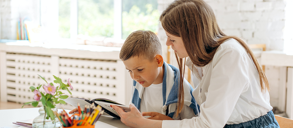 Vorlesen: Eine Frau und ein Junge schauen zusammen ein Buch an