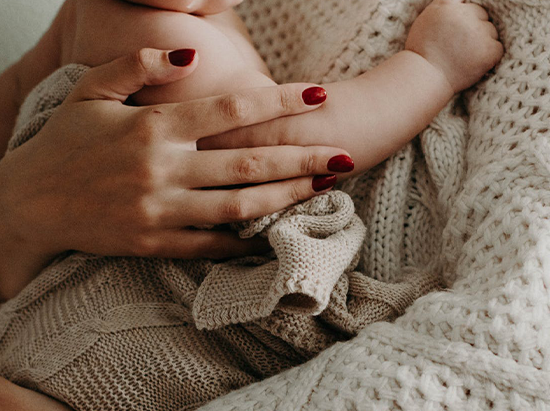 Ein Baby wird von Frauenhänden gehalten