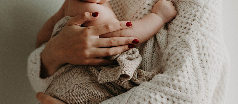 Ein Baby wird von Frauenhänden gehalten