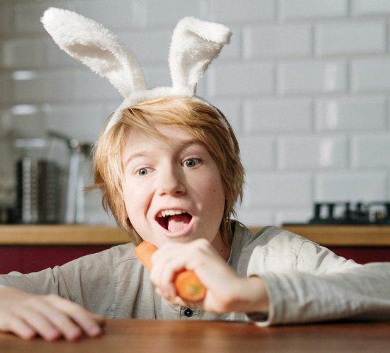 Frohe Ostern wünschen - Ein Junge beißt in eine Karotte