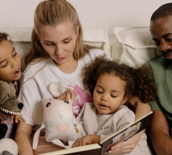 Widmungen für Kinder - Eine Familie schaut gemeinsam ein Buch an
