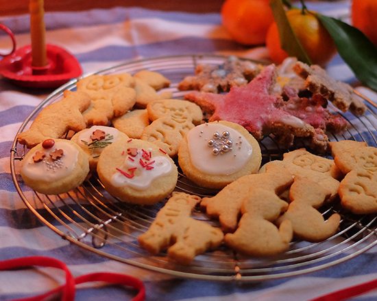 Nahaufnahme eines Tischs bedeckt mit weihnachtlicher Dekoration und verschiedenen Weihnachtskeksen