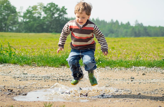 Un niño salta divertido un charco