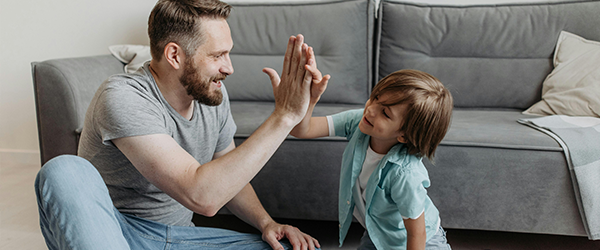 kindliche Sprachentwicklung: Vater gibt Kind High-Five