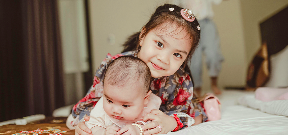 Grosse Schwester umarmt ihr Baby-schwester