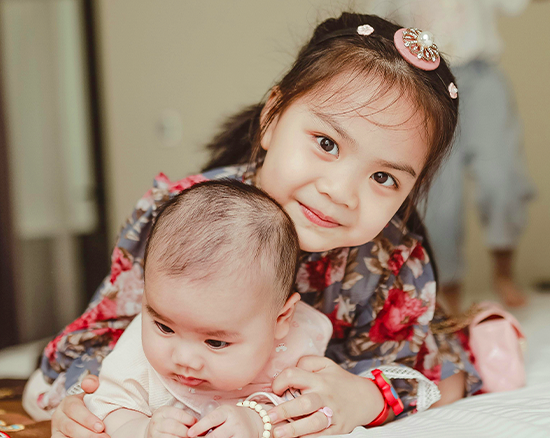 Big sister hugging her baby sister